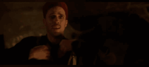 A Man Is Holding A Cross In His Hand In A Dark Room GIF