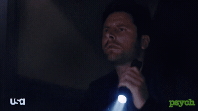 A Man Is Holding A Flashlight In A Dark Room With A Usa Logo In The Corner GIF