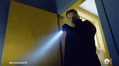 A Man Is Holding A Flashlight In A Doorway With #Chicagopd Written On The Bottom GIF