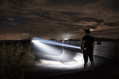 A Man Is Holding A Flashlight While Standing On A Bridge GIF