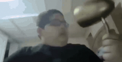 A Man Is Holding A Frying Pan Over His Head In A Blurry Photo . GIF