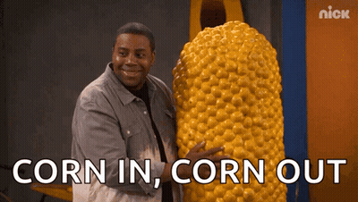 A Man Is Holding A Giant Corn On The Cob With The Words Corn In Corn Out Below Him GIF