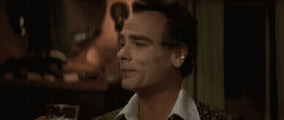 A Man Is Holding A Glass Of Beer In His Hand GIF