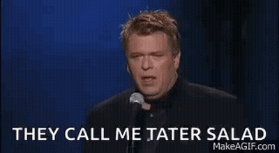 A Man Is Holding A Glass Of Wine And Talking Into A Microphone . GIF