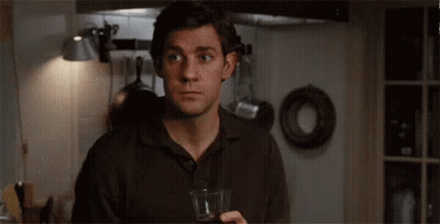 A Man Is Holding A Glass Of Wine In A Kitchen And Says Oh My God . GIF