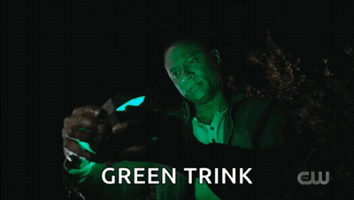 A Man Is Holding A Green Object That Says Green Trink On It GIF