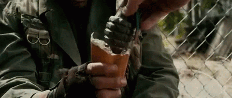 A Man Is Holding A Grenade In His Hand . GIF