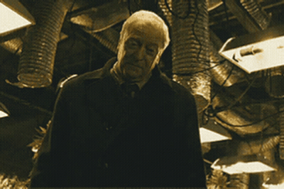 A Man Is Holding A Gun In A Dark Room GIF