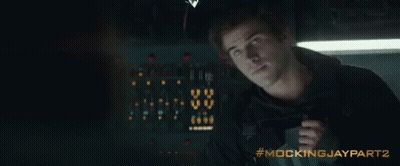 A Man Is Holding A Gun In A Dark Room With The Words Mockingjay Part 2 Written On The Bottom GIF