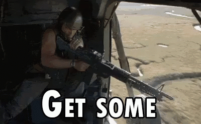 A Man Is Holding A Gun In A Helicopter And The Words `` Get Some '' Are Visible . GIF