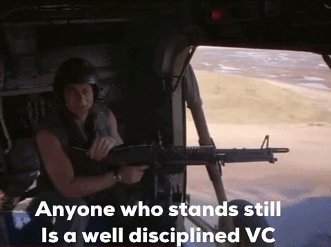 A Man Is Holding A Gun In A Helicopter With The Words Anyone Who Stands Still Is A Well Disciplined Vc Below Him GIF