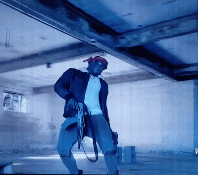 A Man Is Holding A Gun In A Room With The Letter V On The Bottom GIF
