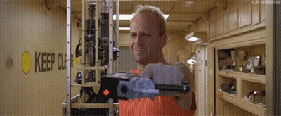 A Man Is Holding A Gun In Front Of A Sign That Says Keep Out GIF