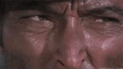 A Man Is Holding A Gun In His Belt While Wearing A Gun Holster . GIF