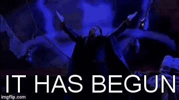 A Man Is Holding A Gun In His Hand In Front Of A Blue Background With The Words `` It Has Begun '' Written On It . GIF