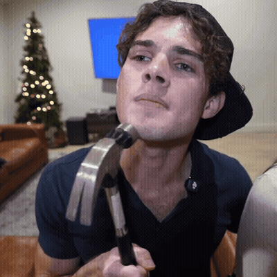 A Man Is Holding A Hammer To His Face GIF