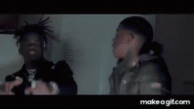 A Man Is Holding A Knife In His Hand While Another Man Is Standing Next To Him . GIF