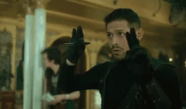 A Man Is Holding A Knife In His Hand While Wearing A Black Glove . GIF