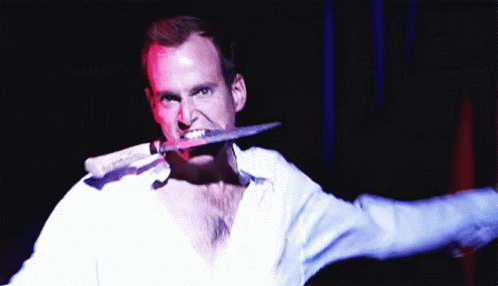 A Man Is Holding A Knife In His Mouth GIF