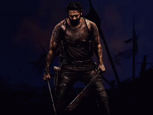 A Man Is Holding A Large Sword In Front Of A Fire GIF