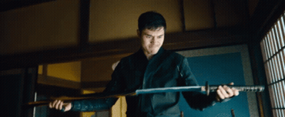 A Man Is Holding A Large Sword In His Hands GIF