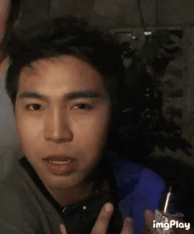 A Man Is Holding A Lighter In His Hand And Making A Face . GIF