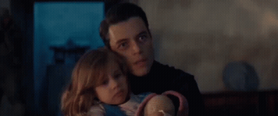 A Man Is Holding A Little Girl In His Arms And The Little Girl Is Looking At The Camera . GIF