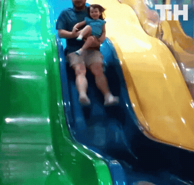 A Man Is Holding A Little Girl On A Slide And The Letters Th Are On The Bottom Of The Slide GIF