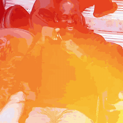 A Man Is Holding A Lollipop And Smiling While Sitting On A Chair GIF