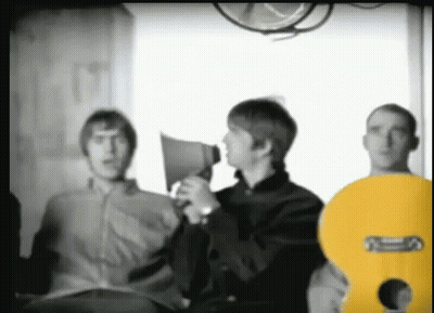 A Man Is Holding A Megaphone While Standing Next To Two Other Men . GIF
