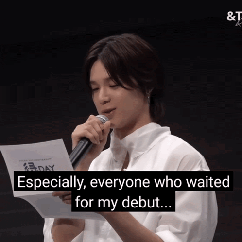 A Man Is Holding A Microphone And Reading A Piece Of Paper With The Words " Especially Everyone Who Waited For My Debut  GIF