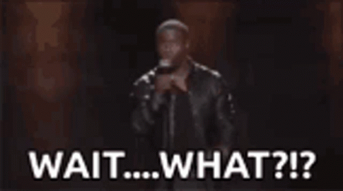 A Man Is Holding A Microphone In Front Of A Crowd And Says `` Wait ... What ? '' GIF