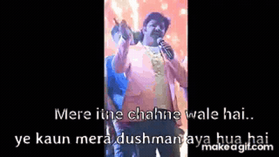 A Man Is Holding A Microphone In Front Of A Crowd While Singing Into It . GIF