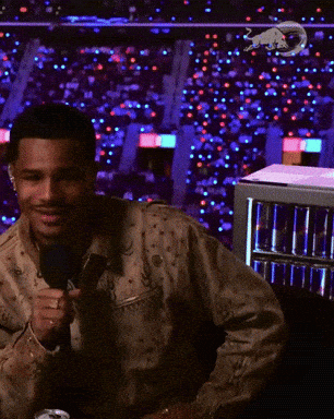 A Man Is Holding A Microphone In Front Of A Fridge Full Of Red Bull Cans GIF