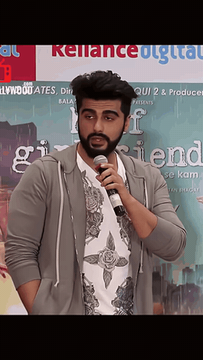 A Man Is Holding A Microphone In Front Of A Poster For Girlfriend GIF