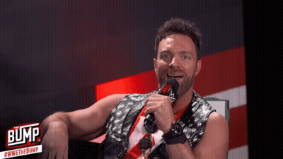 A Man Is Holding A Microphone In Front Of A Sign That Says " Bump " GIF