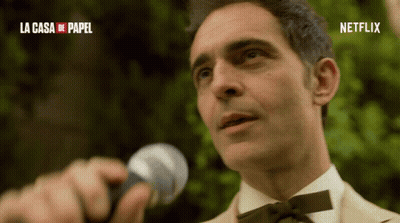 A Man Is Holding A Microphone In Front Of A Sign That Says Netflix GIF