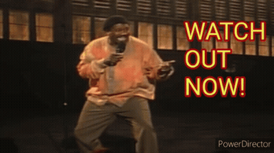 A Man Is Holding A Microphone In Front Of A Sign That Says Watch Out Now .. GIF