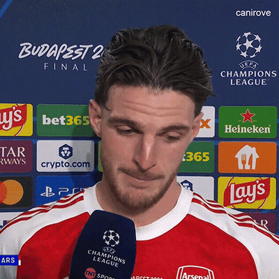 A Man Is Holding A Microphone In Front Of A Uefa Champions League Logo GIF