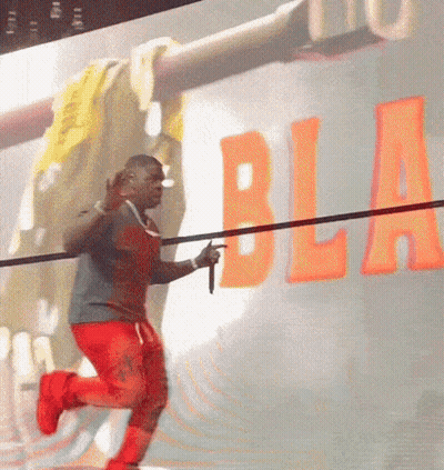 A Man Is Holding A Microphone In Front Of A Wall That Has The Word Bla On It GIF