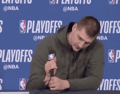 A Man Is Holding A Microphone In Front Of A Wall That Says Playoffs On It GIF