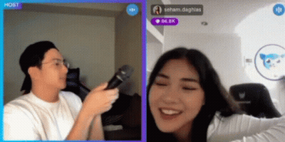 A Man Is Holding A Microphone In Front Of A Woman Who Is Smiling In A Video Chat GIF