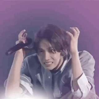 A Man Is Holding A Microphone In His Hand And Making A Face . GIF