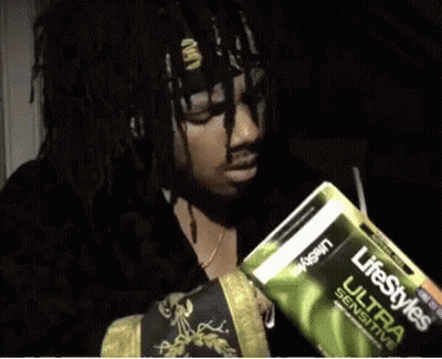 A Man Is Holding A Pack Of Lifestyles Ultra Sensitive Condoms GIF
