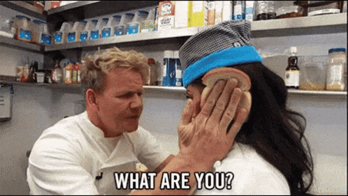 A Man Is Holding A Piece Of Bread Over A Woman 'S Ear And Asking Her What Are You GIF