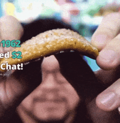 A Man Is Holding A Piece Of Food In His Hand With 1962 Ed $ 2 Chat On The Bottom GIF