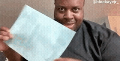 A Man Is Holding A Piece Of Paper In His Hands And Smiling At The Camera . GIF