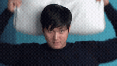 A Man Is Holding A Pillow Over His Head . GIF