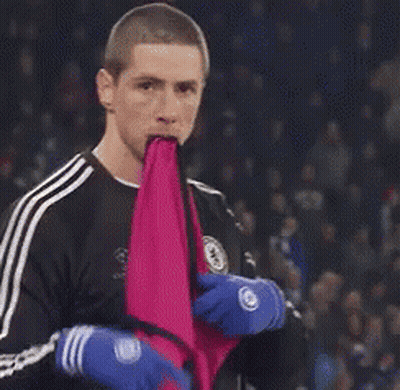 A Man Is Holding A Pink Cloth In His Mouth While Wearing Blue Gloves . GIF