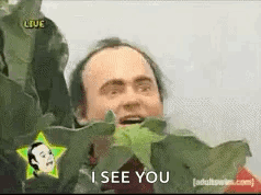 A Man Is Holding A Plant In Front Of His Face And Says `` I See You '' . GIF